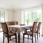 Esszimmer mit Tisch, Stühlen und großen Fenstern zur Außenterrasse.