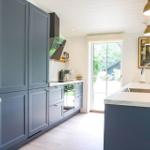 Küche mit blauen Schränken, Marmorarbeitsplatte und Fenster zum Garten.