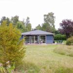 Ein blau gestrichenes Haus mit Terrasse und Garten. Außentisch mit Sonnenschirm.