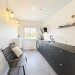 Küche mit dunklen Schränken, Fenster und Bank mit Kissen.