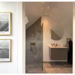 Badezimmer mit Dusche, Waschbecken und runden Spiegel