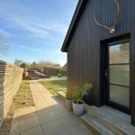 Eingangsbereich mit schwarzer Holzfassade, Pflanzen und Hirschgeweih an der Wand.