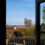 Blick von Balkon auf Felder und Häuser unter blauem Himmel