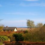 Haus mit Blick auf Meer, umgeben von Bäumen und Feldern.