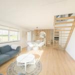 Wohn- und Essbereich mit Holzboden, Sofa und Treppe zur oberen Etage.