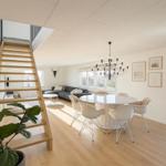 Haus mit Essbereich, Wohnbereich und Holztreppe zur oberen Etage.