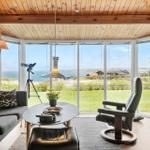 Wohnzimmer mit Holzwand und großem Fensterblick aufs Meer.