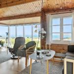 Wohnzimmer mit Holzwänden, großen Fenstern und Meerblick.