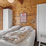 Schlafzimmer mit Holzwand, Bett, Kleiderschrank und Stuhl.