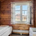 Schlafzimmer mit Holzwand, Bett, Fenster und Kleiderständer.