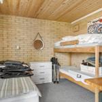 Zimmer mit Doppelstockbett, Kleiderschrank und Holzdecke.