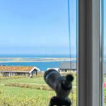 Durch das Fenster ist ein Blick auf das Meer und eine Insel mit Häusern zu sehen.