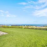 Grüner Garten mit Blick auf das Meer und Ferienhäuser.