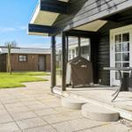 Terrasse mit Grill und Tisch. Hinterhof mit Rasen und Steinweg.