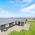 Schwarzes Holzhaus mit Terrasse und Blick aufs Meer.