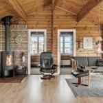 Wohnzimmer mit Holzdecke, Kamin und Sitzgelegenheiten.