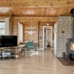 Wohn- und Essbereich mit Kamin, TV und Holzdecke.