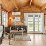 Wohnzimmer mit Holzdecke, Sofa, Sessel und Fernseher.