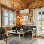 Wohnzimmer mit Holzwand, Sofa, Stuhl und Tisch. Fenster und Tür zur Terrasse.