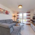 Wohnzimmer mit grauem Sofa, TV und Fenster mit Vorhängen.