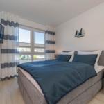 Schlafzimmer mit Bett, TV und Fenster mit Vorhängen.