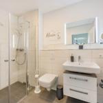 Badezimmer mit Dusche, Waschbecken und Toilette. Wanddekoration mit Ankermotiv.