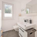 Badezimmer mit Waschbecken, Toilette und Dusche. Fenster mit Jalousie.