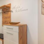 Eingangsbereich mit Holzgarderobe und Schminktisch. Wanddekoration mit Willkommensschild.