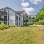 Moderne Wohnanlage mit Balkonen und grünem Gartenbereich.