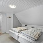 Schlafzimmer mit zwei Betten und Dachschrägen. Weiße Wände und Decke.