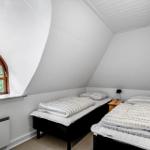 Zimmer mit zwei Betten, Holzfenster und Heizung.