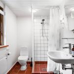 Badezimmer mit Toilette, Dusche und Waschbecken. Fenster, Spiegel und Badewanne.