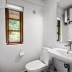 Badezimmer mit Toilette, Waschbecken und Fenster mit Blick auf Grün.