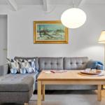 Ein Wohnzimmer mit grauem Sofa, Holztisch und Wandbild.