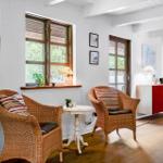 Zwei Rattan-Stühle stehen um einen weißen Tisch herum. Fenster und Türen blicken auf einen Garten.