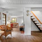 Wohnbereich mit Holzboden, Sitzgelegenheiten und Treppe zur oberen Etage.