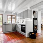 Küche mit Holzfußboden und Backofen. Durchgang zu Wohnzimmer mit Tisch.