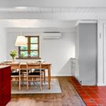 Esszimmer mit Holztisch, Stühlen und Fenster. Rote Fliesen und weiße Wände.