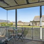 Terrasse mit Tisch und Stühlen, Blick auf Garten und Nachbarhäuser.
