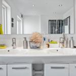 Doppelwaschbecken mit Spiegel, Dusche und Badzubehör.