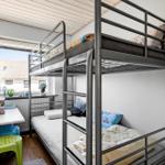 Zimmer mit Doppelstockbett, Fenster, Schreibtisch und Stühlen.