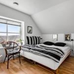 Schlafzimmer mit Doppelbett, Fenster, Stühlen und Wandbildern.