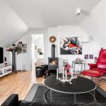 Wohnzimmer mit Kamin, rotem Sessel und Fernseher an der Wand.