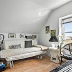 Zimmer mit Schlafcouch, Stuhl und Fensterblick auf Felder.