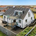 Modernes weißes Haus mit Balkon und Terrasse in ländlicher Umgebung.