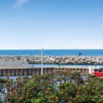 Rotes Boot liegt am Hafen, Blick auf das Meer und Steinschutzwall.