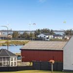 Haus mit Blick auf Wasser, Windräder und Kitesurfer.
