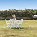 Hinterhof mit weißem Tisch und Stühlen, Blumen und Gartenmöbeln.