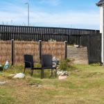 Hinterhof mit zwei schwarzen Stühlen, Zaun und Grasfläche.