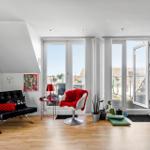 Wohnzimmer mit Blick auf Balkon, rotem Sessel und Kunst an den Wänden.